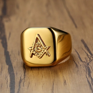 Gold Freemasonry signet ring with compass and square emblem on dark wood background