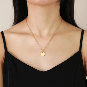 Detail of a minimalist gold round pendant necklace with a small zircon on a female model
