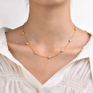 Detail of a gold choker necklace with eight round-cut white zircons worn by a female model