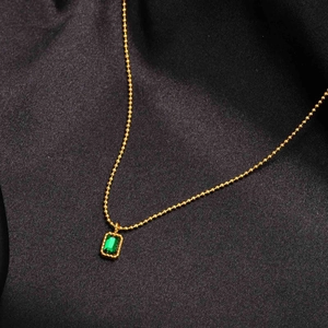 Elegant gold bead chain necklace featuring a rectangular emerald zircon pendant on black silk