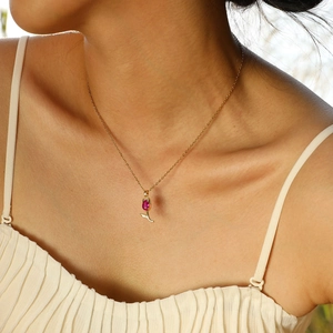 Gros plan d'un pendentif tulipe doré avec zircon rouge porté sur le cou d'une femme