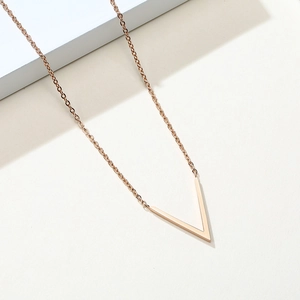 Collier avec pendentif en V en acier inoxydable or rose sur un fond minimaliste chic