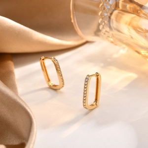 Detail of 18K gold rectangular hoop earrings with pave-set zircon on champagne silk
