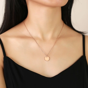 Detail of rose gold circle pendant necklace with small zircon on a minimalist cross chain