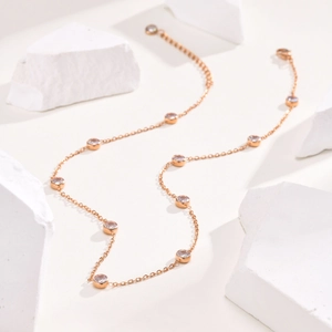 Detail of rose gold titanium necklace featuring ten bezel-set round white zircon stones