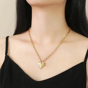 Detail of gold paperclip chain necklace with LUCKY heart pendant worn on the neck