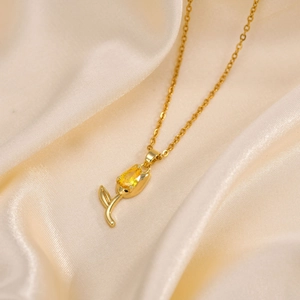 Vue macro du collier tulipe dorée avec zircon jaune poire sur tissu de soie lisse