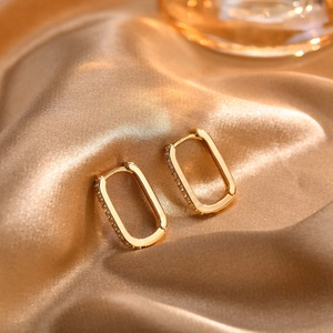Detail of 18K gold hoop earrings with white zircon on champagne silk background