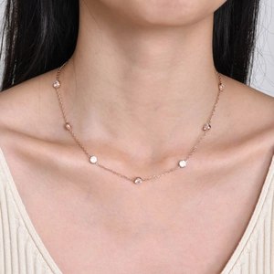 Close-up of a rose gold titanium steel necklace with white zircon stones on a model