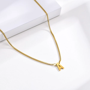 Gros plan d'un collier en acier inoxydable doré avec un pendentif lettre A majuscule