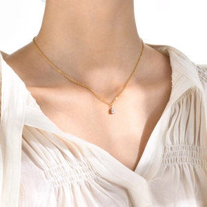 Élégant collier doré avec pendentif en zircon poire porté sur le cou d'une femme
