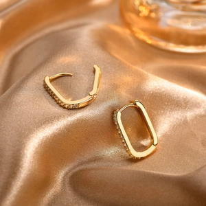 Detailed macro view of 18K gold-plated U-shaped hoop earrings with sparkling zircon inlay