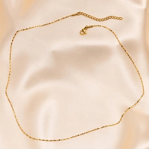 Close-up of golden stainless steel chain with lobster clasp on elegant champagne silk