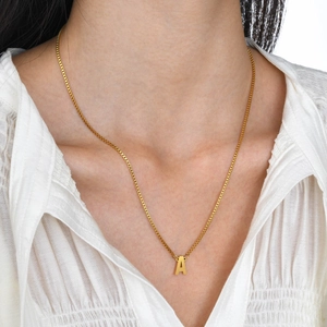 Collier chaîne box dorée avec pendentif lettre A porté par un mannequin sur une chemise