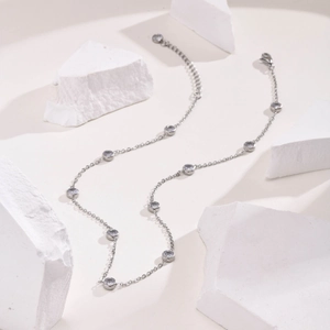 Macro detail of silver stainless steel chain with round clear zircon stones and lobster clasp