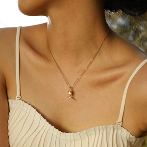 Détail d'un pendentif tulipe doré avec zircon rouge en forme de goutte sur une chaîne