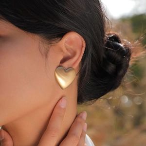 Detailaufnahme der gebürsteten 18K vergoldeten Herz-Ohrstecker an einem weiblichen Model