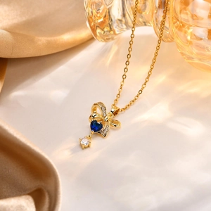 Dettaglio della collana a fiocco dorata con zircone a cuore blu su seta raffinata