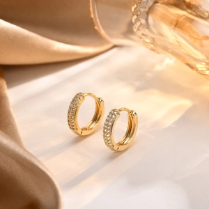 Detailed shot of 18K gold hoop earrings with pavé zircon on elegant satin fabric