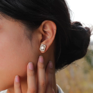 Macro view of a 15K gold square halo stud earring with emerald-cut cubic zirconia
