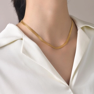 Close-up of double-layered 18k gold flat chain necklace on a model wearing a white shirt