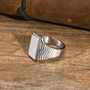 Macro di anello con sigillo d'argento con trama laterale su sfondo di legno e pelle scura