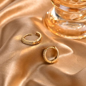 Detail of 18K gold hoop earrings with micro-pave crystals on golden silk background