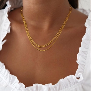 Détail d'un collier double doré superposé avec trombones et perles sur le cou du mannequin
