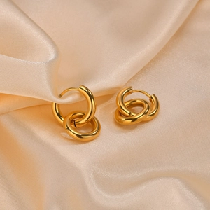 Detail of gold-plated triple interlaced hoop earrings on champagne silk fabric