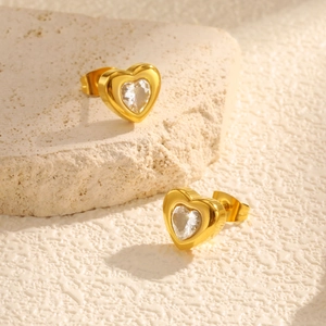 Elegant gold-plated heart stud earrings with white cubic zirconia on a stone surface