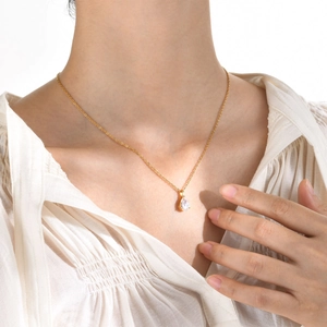 Détail d'un collier en acier doré avec pendentif zircon goutte d'eau sur mannequin