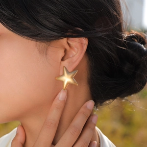 Matte 18K Goldstern-Ohrstecker am Modell im großen, minimalistischen 3D-Design