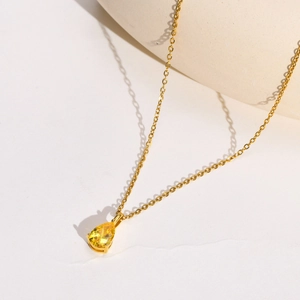 Détail d'un collier en acier doré avec pendentif en zircon jaune de forme poire