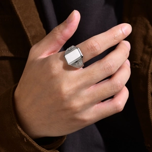 Dettaglio di un anello a sigillo argento con intarsio bianco e scanalature laterali da uomo