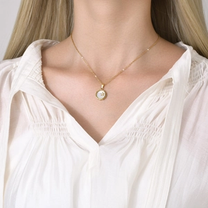Détail du pendentif étoile dorée sur disque en nacre avec chaîne en or élégante