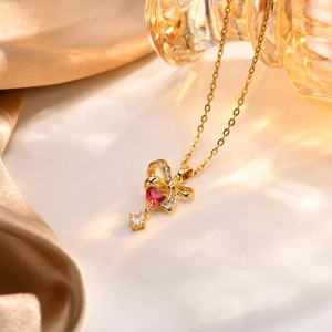 Dettaglio della collana cuore dorata con zircone rosso e fiocco di cristallo su seta