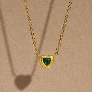 Detailed close-up of golden heart pendant with vibrant emerald green heart-shaped zircon