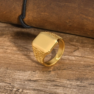 Dettaglio di un anello a sigillo quadrato dorato con eleganti scanalature laterali