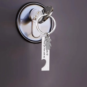 Close-up of stainless steel keychain with engraved tag and girl charm on door key