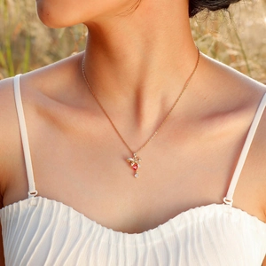 Dettaglio della collana dorata con fiocco e pendente a cuore rosso su modella
