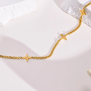 Close-up of gold star pendant necklaces on textured white stone with detailed stone setting