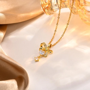 Dettaglio della collana con ciondolo a cuore e fiocco dorato con pietre di zirconi