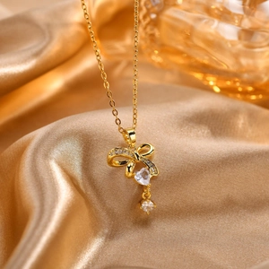 Dettaglio della collana con fiocco d'oro e zircone a cuore su sfondo di seta
