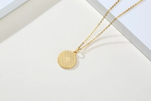 Détail macro du collier doré en acier inoxydable avec pendentif rond texturé