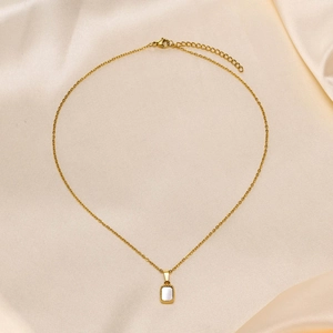 Detail of gold chain necklace with rectangular white shell pendant and beaded edge decor