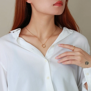 Gros plan d'un collier avec pendentif cercle doré et bague assortie sur un mannequin