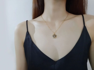 Détail du collier médaille œil bleu en or avec zircon serti sur le cou du mannequin