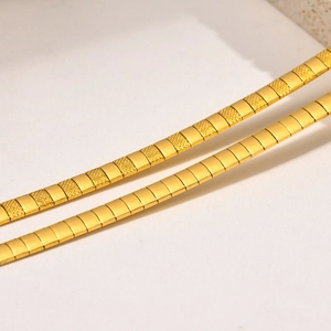 Macro detail of golden hammered flat snake chain necklace with textured segments