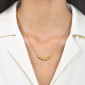 Elegant gold stainless steel necklace with five bean pendant worn by a model