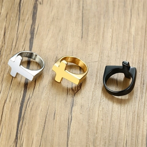 Detailed view of cross rings in silver, gold and black finishes on a wood background